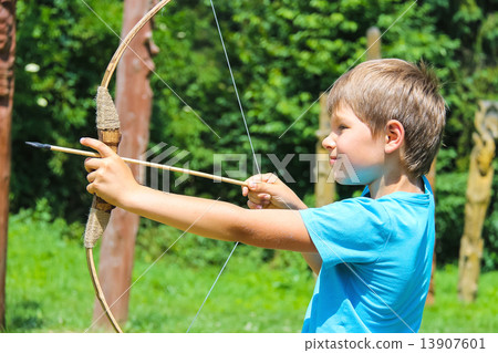 The kid shoots a bow in the park 13907601
