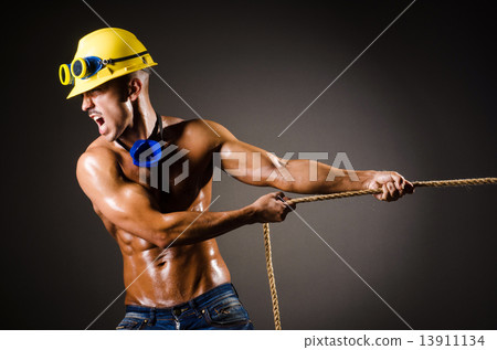 Nude builder pulling rope in darkness 13911134