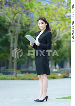 One young successful Chinese businesswoman using tablet iPad along promenade One young successful Chinese businesswoman using tablet iPad along promenade 13920982