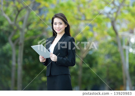 One young successful Chinese businesswoman using tablet iPad along promenade 13920983