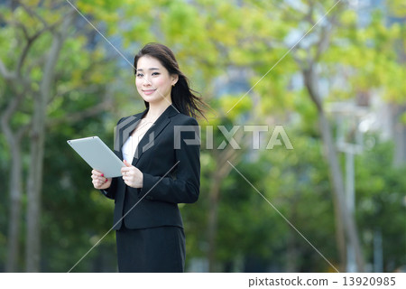 One young successful Chinese businesswoman using tablet iPad along promenade One young successful Chinese businesswoman using tablet iPad along promenade 13920985