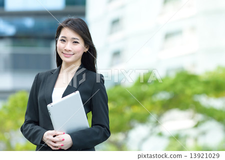One young successful Chinese businesswoman holding tablet iPad along promenade One young successful Chinese businesswoman holding tablet iPad along promenade 13921029