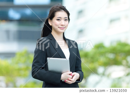 One young successful Chinese businesswoman holding tablet iPad along promenade 13921030