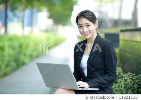 One young successful Chinese businesswoman using laptop sitting along promenade 13921110