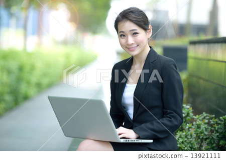 One young successful Chinese businesswoman using laptop sitting along promenade 13921111