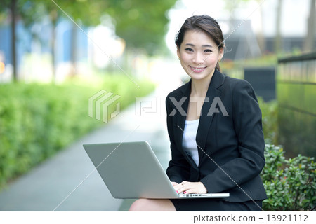 One young successful Chinese businesswoman using laptop sitting along promenade 13921112