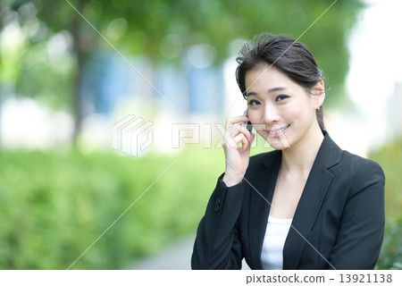 One young successful Chinese businesswoman using mobile phone along promenade 13921138