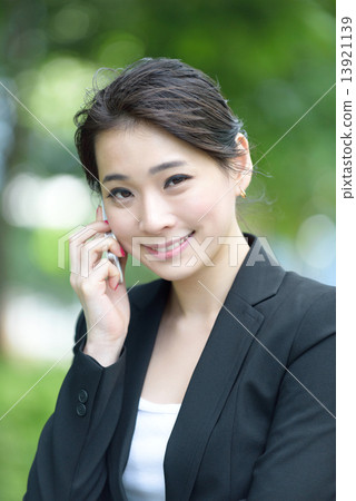 One young successful Chinese businesswoman using mobile phone along promenade 13921139
