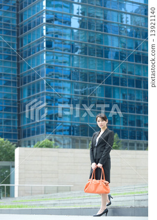 One young successful Chinese businesswoman standing outside glass office building 13921140