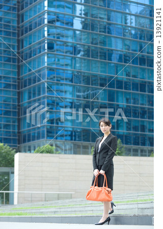 One young successful Chinese businesswoman standing outside glass office building 13921141