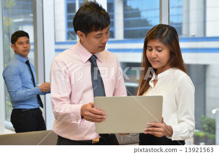 Asian business colleagues working around a laptop 13921563