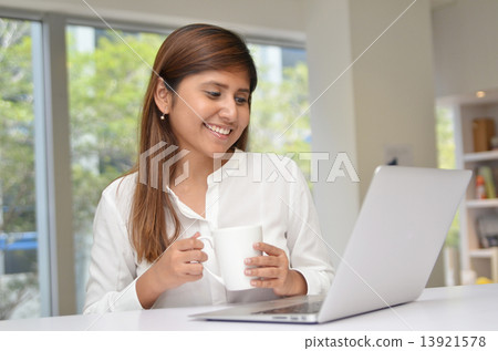 Young indian businesswoman on a coffee break. Using tablet compu Young indian businesswoman on a coffee break. Using tablet compu 13921578