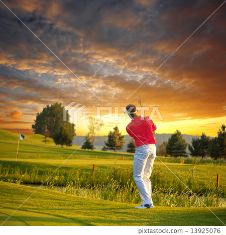 Man playing golf against colorful sunset 13925076