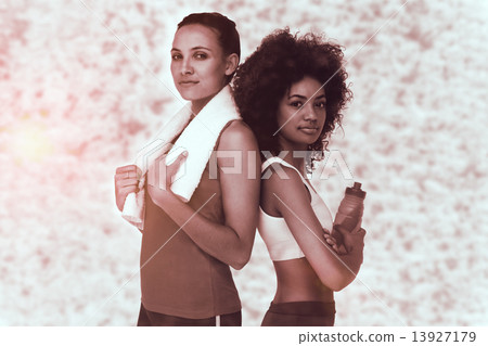 Composite image of fit women standing with waterbottle and towel 13927179