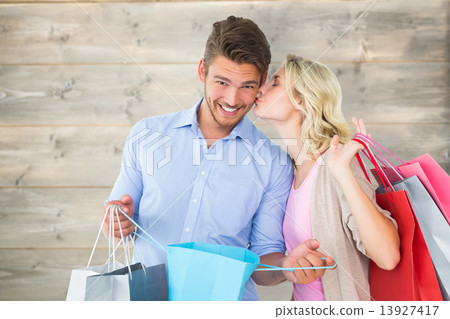 Composite image of attractive young couple holding shopping bags 13927417