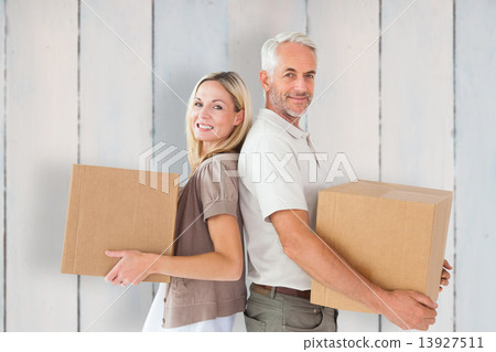 Composite image of happy couple holding moving boxes Composite image of happy couple holding moving boxes 13927511