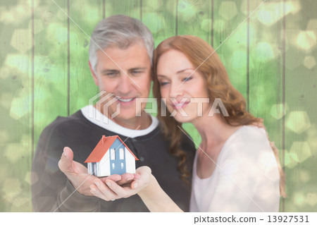 Composite image of casual couple holding small house Composite image of casual couple holding small house 13927531