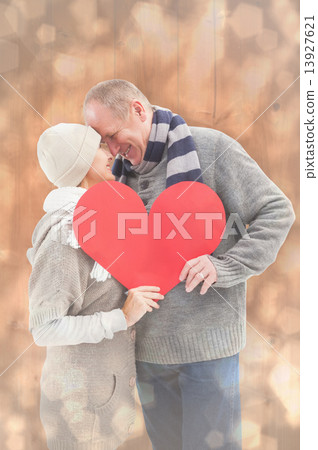 Composite image of happy mature couple in winter clothes holding 13927621