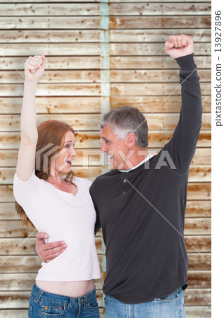 Composite image of casual couple cheering and smiling Composite image of casual couple cheering and smiling 13927896
