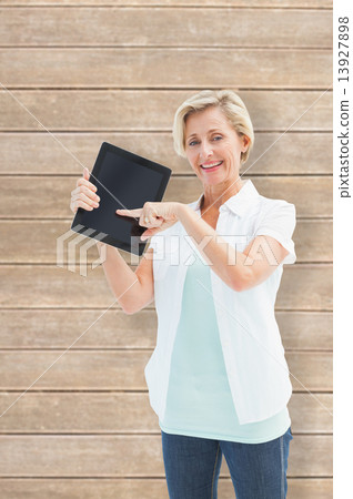 Composite image of happy mature woman pointing to tablet pc Composite image of happy mature woman pointing to tablet pc 13927898