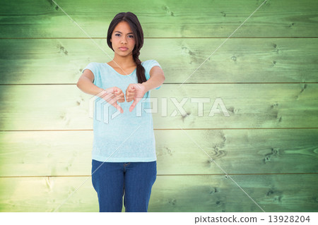 Composite image of disappointed brunette giving thumbs down 13928204