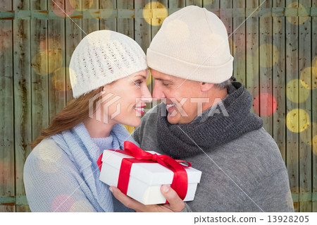 Composite image of casual couple in warm clothing holding gift 13928205