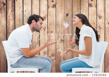 Composite image of couple sitting on chairs arguing 13928568