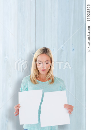 Composite image of serious woman holding torn sheet of paper 13928896