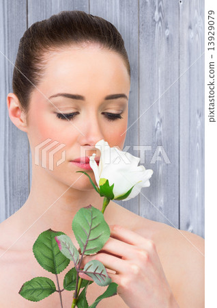 Composite image of beautiful brunette smelling white rose 13929079