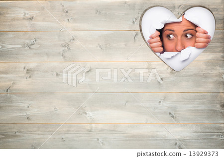 Composite image of young woman looking through paper rip 13929373