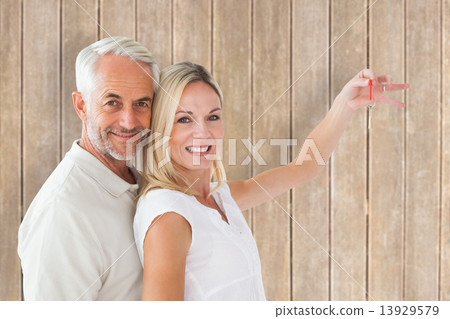 Composite image of happy couple showing their new house key Composite image of happy couple showing their new house key 13929579