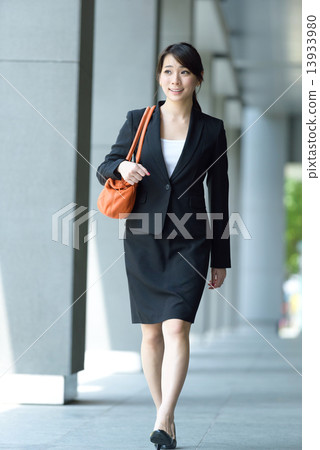 One young successful Chinese businesswoman walking along office building walkway 13933980