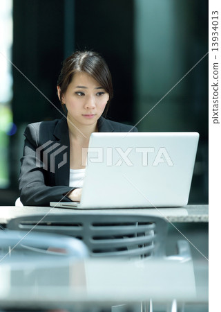 One young successful Chinese businesswoman using laptop along promenade 13934013