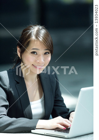 One young successful Chinese businesswoman using laptop along promenade One young successful Chinese businesswoman using laptop along promenade 13934023