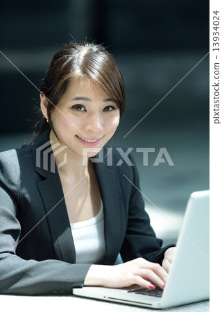 One young successful Chinese businesswoman using laptop along promenade One young successful Chinese businesswoman using laptop along promenade 13934024