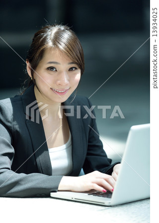 One young successful Chinese businesswoman using laptop along promenade One young successful Chinese businesswoman using laptop along promenade 13934025