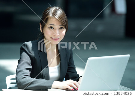 One young successful Chinese businesswoman using laptop along promenade One young successful Chinese businesswoman using laptop along promenade 13934026