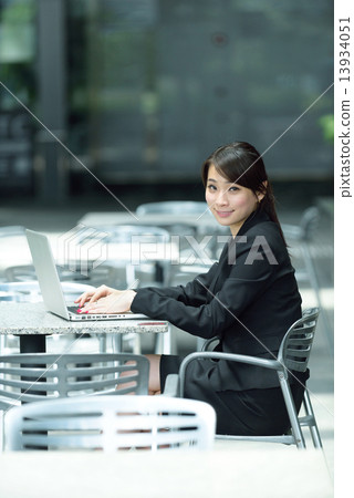 One young successful Chinese businesswoman using laptop along promenade 13934051