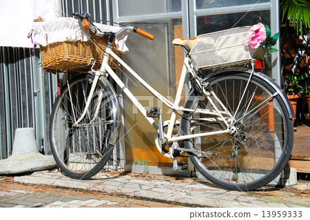 Bicycle with wicker basket stands near wall 13959333