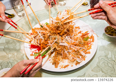 Mixing and tossing Yee Sang dish with chop sticks. Yee Sang is delicacy during Chinese New Year. 13974226