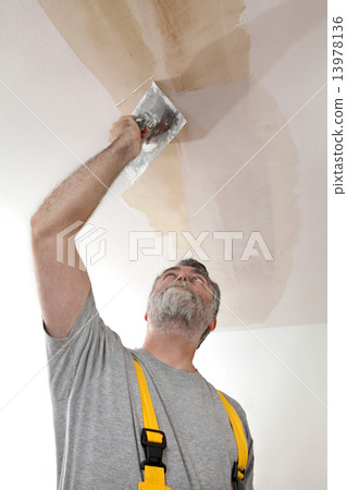Worker repairing plaster at ceiling 13978136