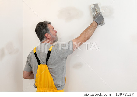 Worker repairing plaster at wall Worker repairing plaster at wall 13978137