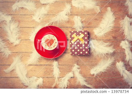 Coffee and feathers with gift on wooden background. Coffee and feathers with gift on wooden background. 13978734