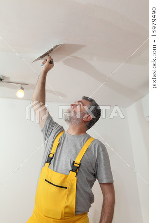 Worker repairing plaster at ceiling 13979490