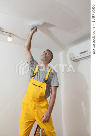 Worker repairing plaster at ceiling Worker repairing plaster at ceiling 13979500