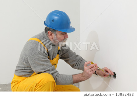Electrician at construction site testing installation Electrician at construction site testing installation 13982488