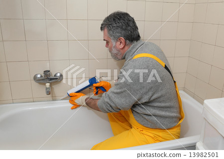 Worker caulking bath tube and tiles 13982501