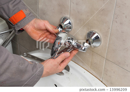 Plumber fixing faucet in a bathroom 13996209