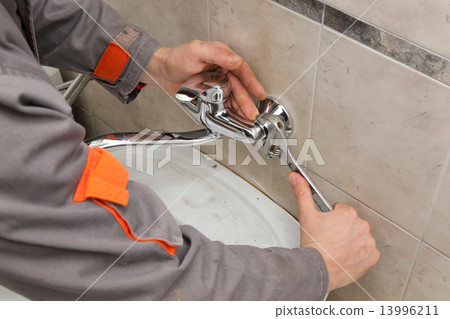 Plumber fixing faucet in a bathroom 13996211