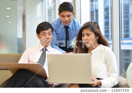 Asian business colleagues working around a laptop Asian business colleagues working around a laptop 13997359